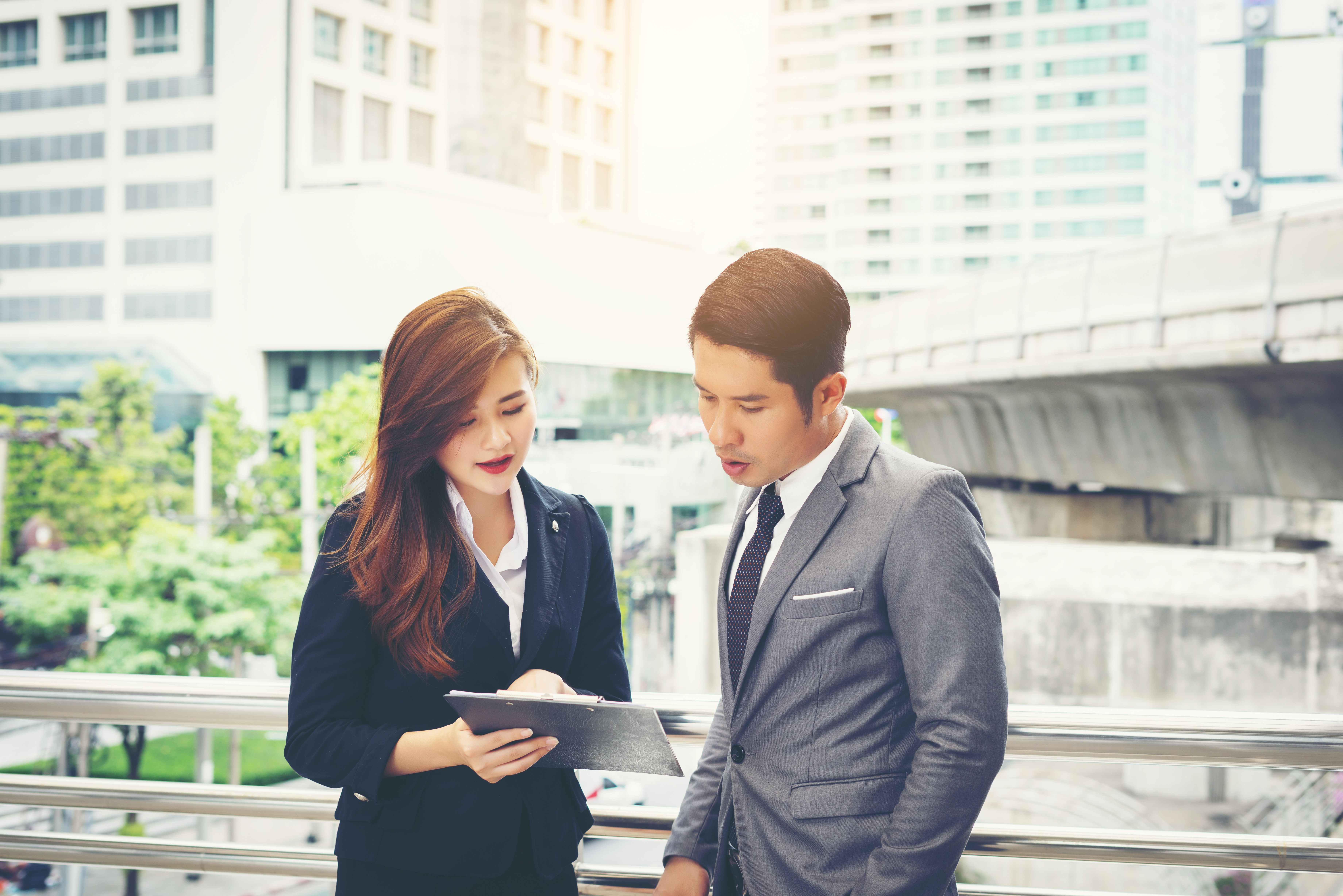 business-man-pointing-document-with-smile-discussing-something-with-her-coworker-while-standing-front-office.jpg